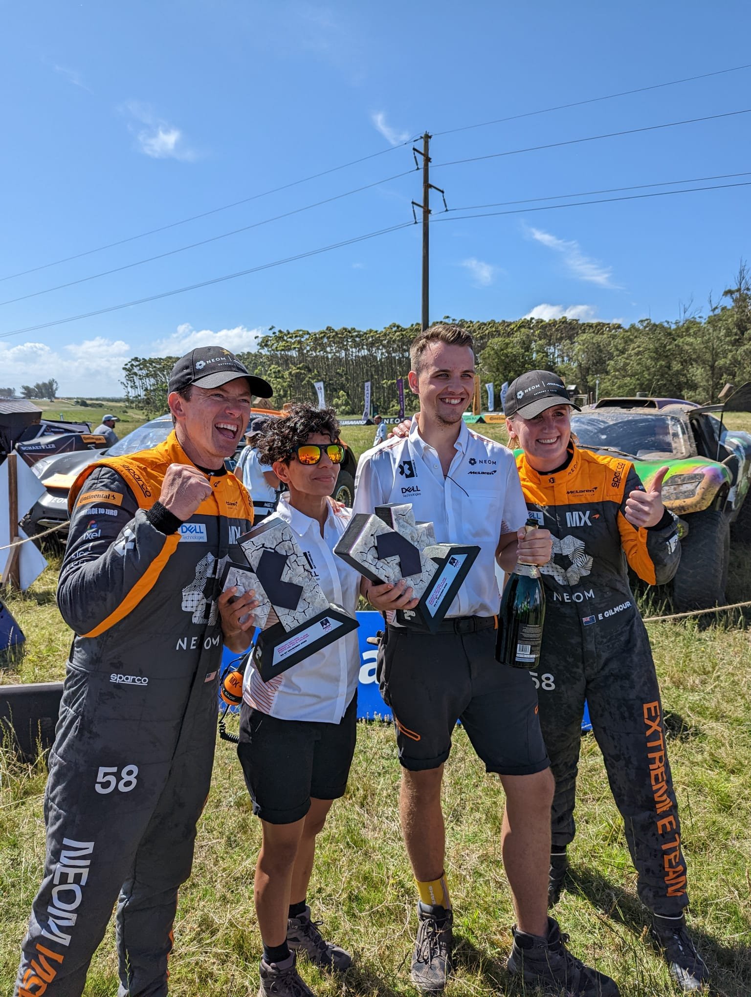 Chris Cousall standing with a racing team in a paddock.