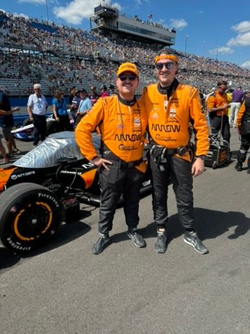 Chris Cousall standing beside an IndyCar on the grid.