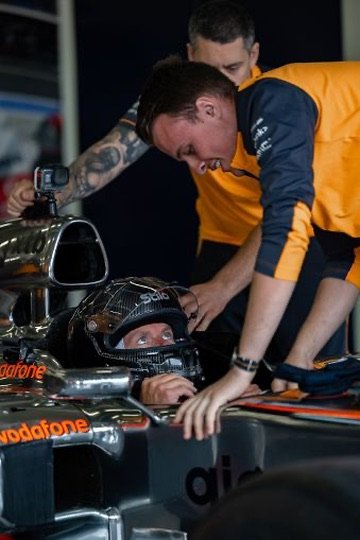 Chris Cousall leaning into a Formula 1 car during a night garage session.