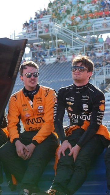 Chris Cousall seated beside a race driver on the grid.